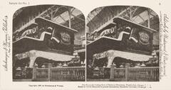 This black and white stereoscopic image features two images of a view of an enormous stove in an iron building and next to a railing.  It is surrounded by the text: Sample Set No. 1; Strohmeyer &amp; Wyman, Publishers; The Mammoth Cooking Stove of Barbecue Dimensions, World’s Fair, Chicago U.S.A., Estufa de Coerua Mammuth de grandes dimensiones, Exposicion Universal, Chicago, E.U.A.<br />