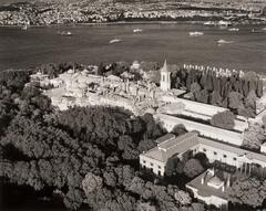 This photograph depicts an aerial view of a palace next to a harbor.