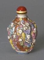 A snuff bottle with high relief images of luohan (buddhist sages/arhats) dressed in different colored robes (purple, blue, yellow, pink, and red). There are different colored swirls surrounding them (purple, blue, yellow, pink, and red). There is are red stopper and a gold collar.