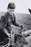 A soldier loads rounds of ammunition into an aircraft.