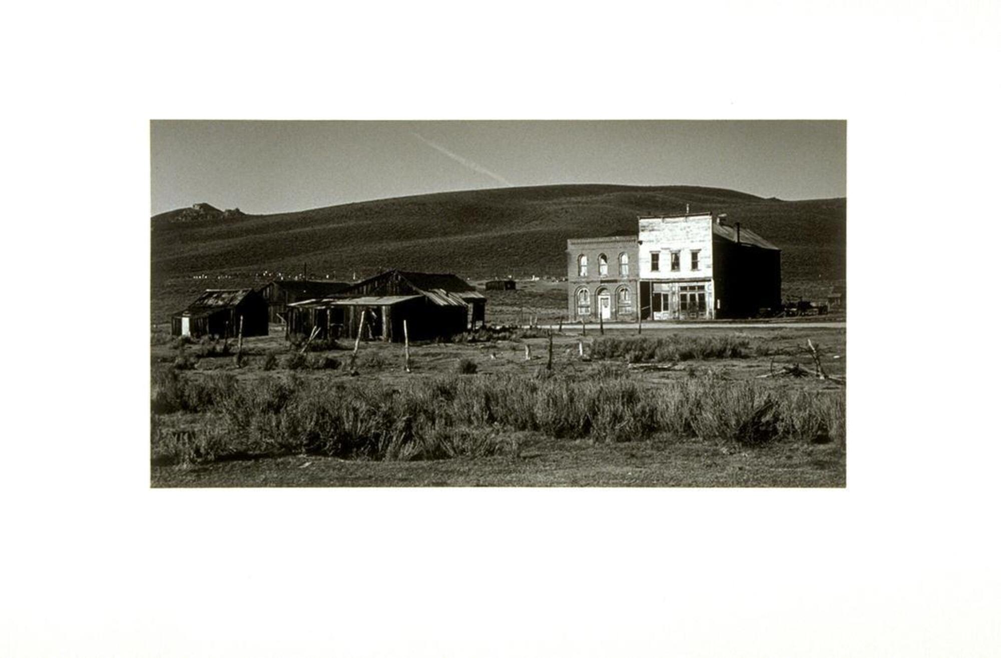 Photograph of shacks and abandoned houses in a landscape.
