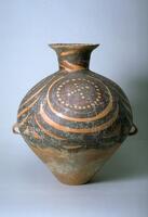 A light reddish-buff earthenware <em>guan (</em>罐) jar with a wide globular upper body and conical lower body on a flat base, and a tall narrow neck with an everted rim. There are two diametrically opposed lug handles at the waist. The upper half of the body is painted with black and red pigments to depict four whirls of concentric circles. Each contains a roundel made of joined circles, which also create a cross through the center. The four circular motifs are confined between solid band borders, with a garland border below. Around the neck are bold thick black chevrons.