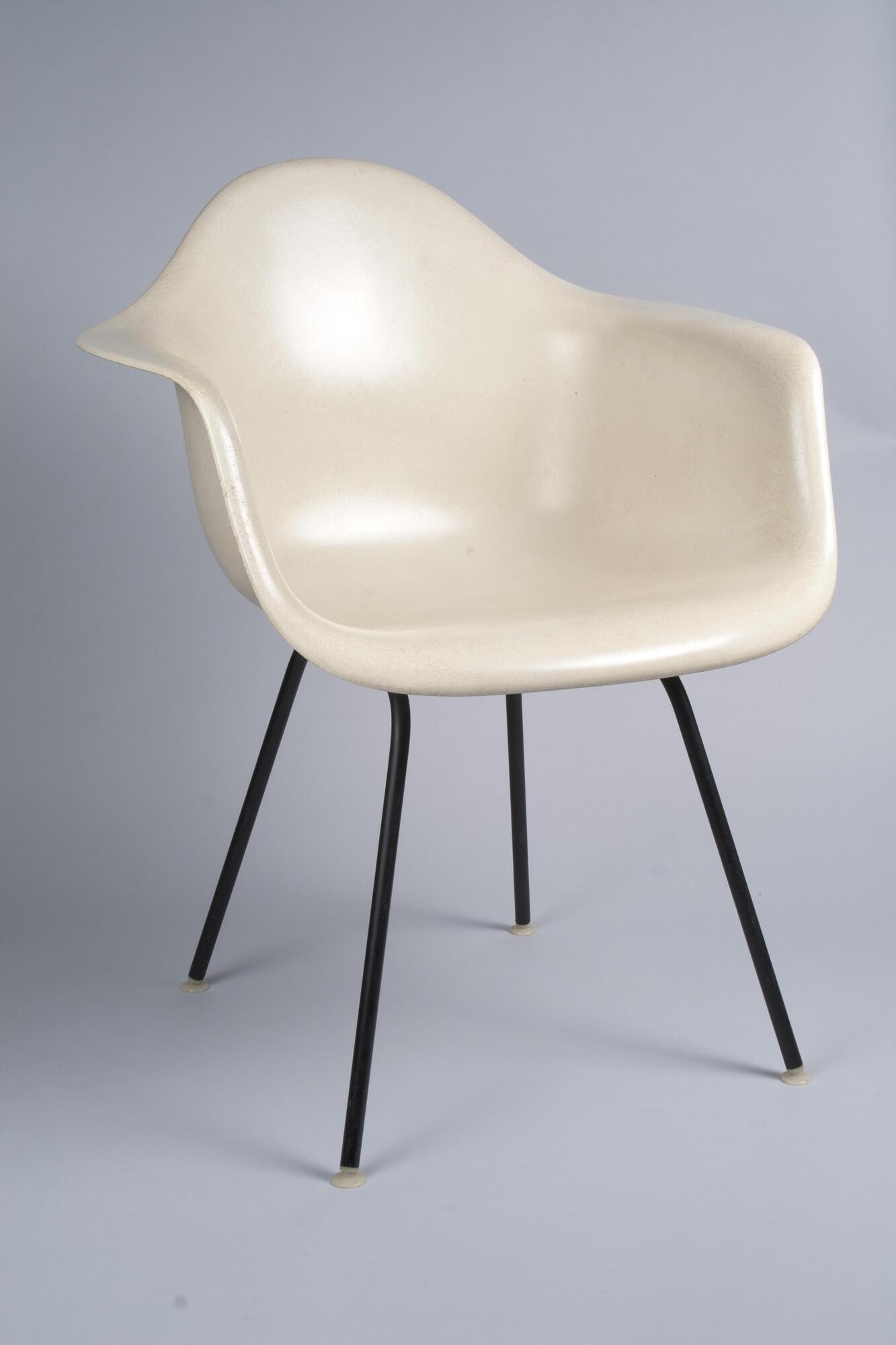 White armchair consisting of a single plastic "shell" mounted on a black, four-legged metal base (an "H" base).