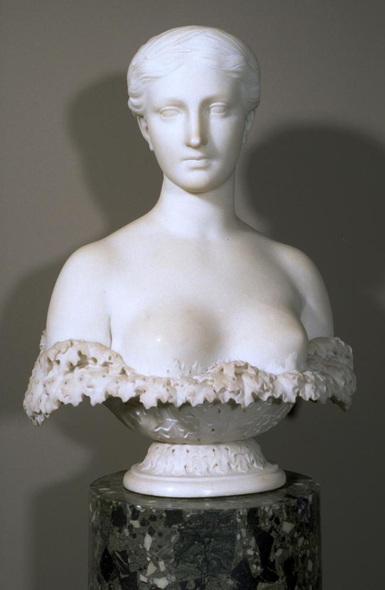 Bust-length white marble sculpture of a young female figure crowned with a plait of wheat and framed along the bottom with a wreath of sculpted acanthus leaves.