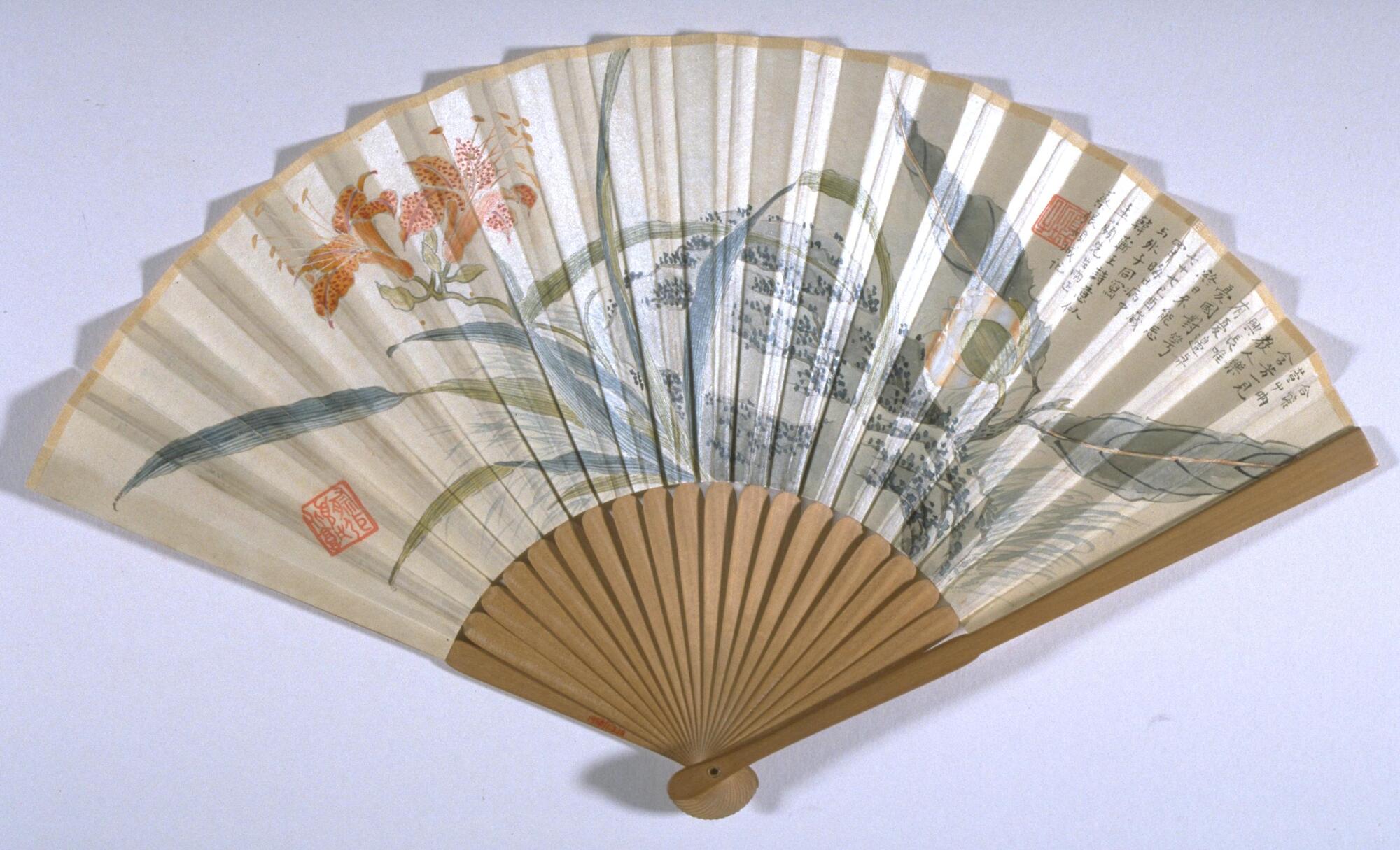 A fan with depictions of chrysanthemums, tiger lilies, and rocks.
