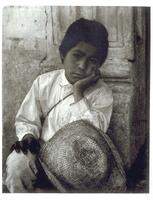 This is a photograph of a young boy in Uruapan, Mexico. The boy sits with his left hand on his knee and his chin resting in his right hand. 
