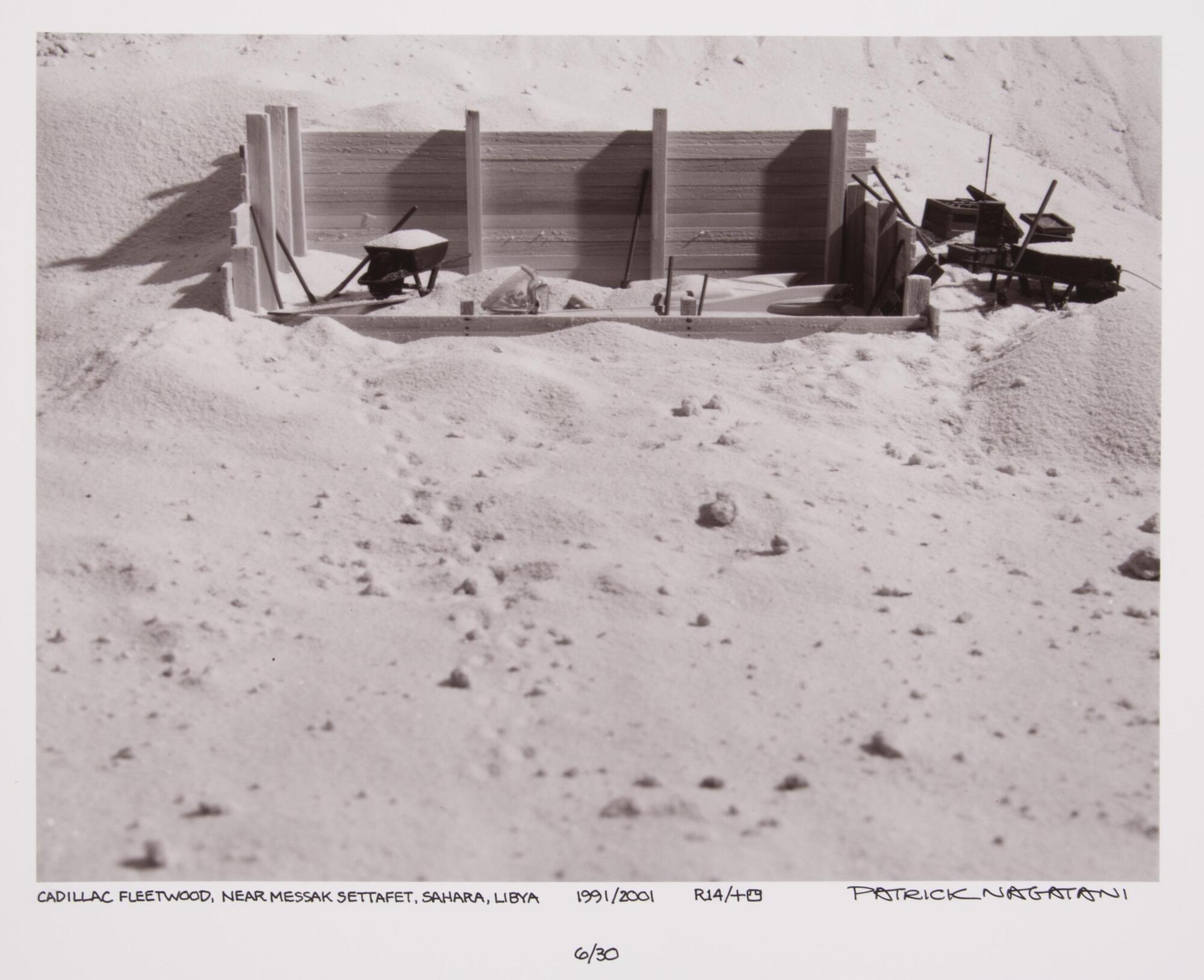 Car under excavation in a desert scene. There is a wooden framework around the car.
