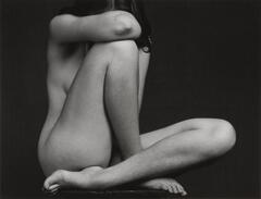 Female nude seated with legs crossed, knee up, face hidden in arm.