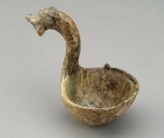 A red, round bottom, ovoid earthenware ladle with a long curved dragon headed handle.  It is covered in a green lead glaze with iridescence and calcification. 