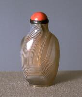 An agate snuff bottle with a silver collar and coral stopper.