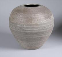 Vase with a narrow bottom and wide top. Gray ash glaze with green matte glaze on upper part, incised rings.