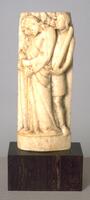 This carved bone sculpture depicts John the Evangelist in profile with his hands held before him, bowing his head in mourning. A male figure wearing a knee-length robe stands on the right and holds a club in his left hand. A second male figure appears behind the saint in a similar pose of grief.