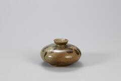 Stoneware oil bottle with cup-shaped mouth and body in the shape of a Go gaming piece, or Baduk. The body is decorated with painted floral sprays and covered by celadon glaze.<br />
&nbsp;
<p>The bottle is embellished with chrysanthemums with p&acirc;te-sur-p&acirc;te decorative technique and with the leaves in iron- brown. There are three refractory spur marks on the low foot. It has a dark ground color that appears like deep gray. Glaze on the body is oxidized, producing areas of yellow- brown color. The rim of the mouth shows traces of repair.<br />
[<em>Korean Collection, University of Michigan Museum of Art</em> (2014) p.131]</p>
