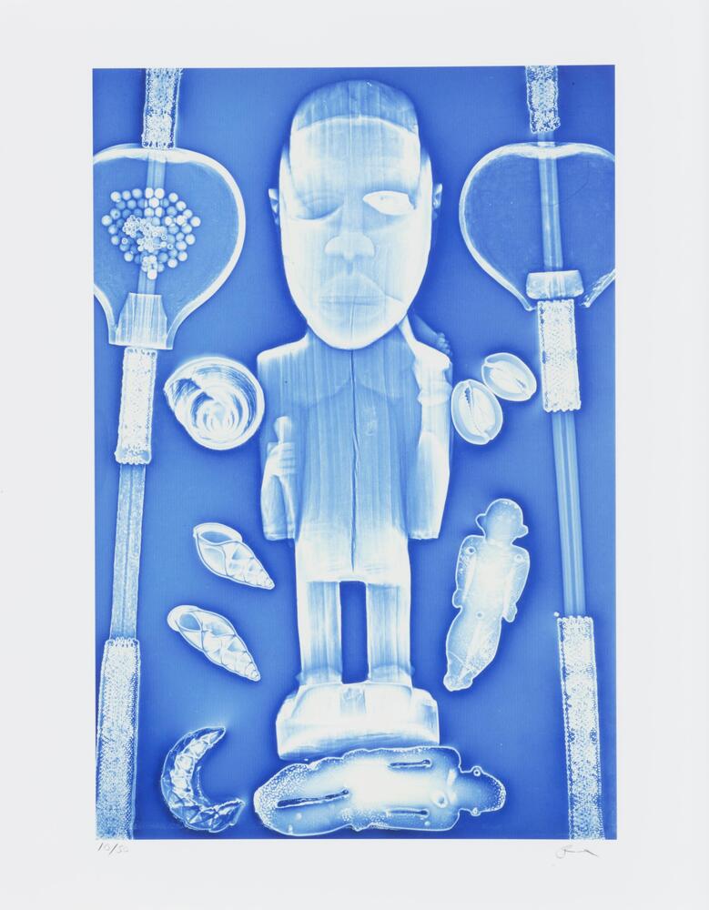 A color photograph with hues of blue and white featuring a standing figure in the center. The figure looks straight out at the viewer and is surrounded by small shell-shaped objects. On the right and left sides of the image are two vertical instruments with rounded forms at the upper portions.
