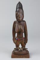 Standing wood figure of a woman with hands at side, staring directly ahead. Hair is pilled on the top of the head.