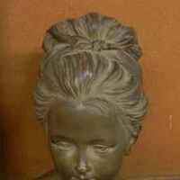 The bust of a young girl, with her hair swept back and held up high on the back of her head. She looks down and to her left, the viewer&#39;s right.&nbsp;