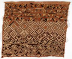Square panel with hemmed edges divided into three sections. The upper section consists of alternating trianglular designs with red, tan and brown color fields. The middle section consists of a diamond pattern while the lower section consists of black and tan alternating trianglular designs. 
