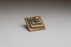 Gold-weight in the shape of five stepped squares. 