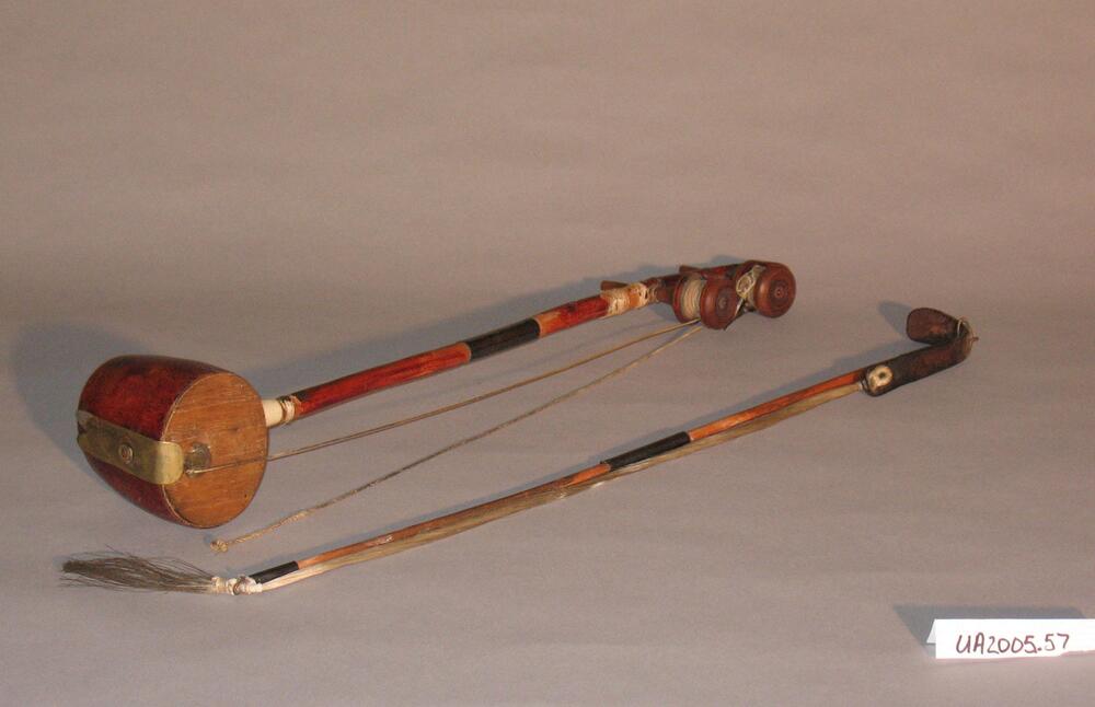 An instrument consisting of a hollow sound box, a bamboo beck, two pegs in the upper neck wound with strings, two strings, and a bow. The sound box is made of sanyuja wood.<br />
<br />
This is a traditional Korean musical instrument with two strings. Sound is produced by the friction between strings made from several strands of thin silk thread and bowstrings made of horsehair. Its unique sound has earned the haegeum alternative, onomatopoeic names such as gaenggaengi and aenggeum. The instrument consists of a hollow sound box, a bamboo neck, two pegs in the upper neck each wound with a string, the strings themselves, and a separate bow. The pegs are currently detached from the neck. The sound box is made of sanyuja wood (Xylosma congestum).
<p>[Korean Collection, University of Michigan Museum of Art (2017) p. 288]</p>
<br />
&nbsp;