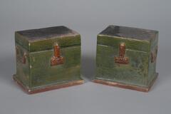 A pair of green glazed rectangular chests on amber glazed dais, with amber central locks and handles on opposing sides.  