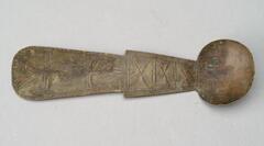Spoon with a wide, flat two-tiered handle. The lower half of the handle is decorated with three 'bow-tie' designs. The upper portion of the handle is decorated with an animal with a pointed head, a lozenge-shaped body, and a two-pointed tail. 