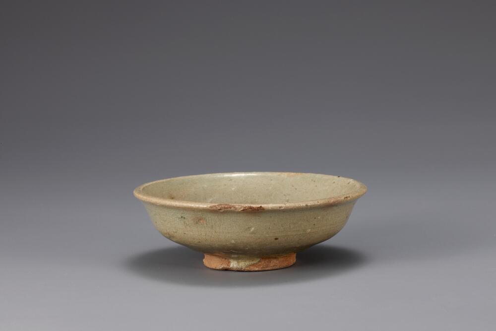 This dish is decorated only on the inner wall with white inlaid design of several concentric circles. Many of inlaid buncheong ware of this type, with simple decorations, was found in the waste deposit of buncheong kilns in the areas of Ui-dong and Gwanaksan Mountain in the vicinity of Seoul. The foot is unglazed, revealing the clay body, and there remain three spur marks. The glaze is pale blue-green in color and it is well-fired.<br />
[Korean Collection, University of Michigan Museum of Art (2014) p.151]