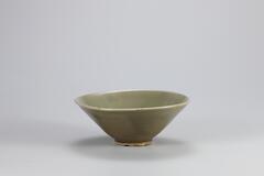 <p>This bowl exemplifies early-tenth century celadon forms influenced by Chinese Yue ware. It has a halo-shaped foot (haemurigup), a characteristic of Yue ware. It is a high-quality celadon made from fine clay, coated by highly transparent glaze. Surface is plain while displaying crackles on its inner surface and parts of its outer surface. Many similar vessels were excavated from the Kilns no. 9 and no. 10 at Yongun-ri, Gangjin-gun, Jeollanam-do. Refractory spur marks created during firing remain in five places on the rim of the foot.<br />
[<i>Korean Collection, University of Michigan Museum of Art </i>(2014)&nbsp;p.88]</p>
Stoneware tea bowl with celadon glaze.