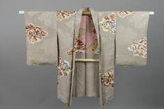 <p>cream-gray chirimen komon haori with interwoven karahana (chinese stylized flowers) arranged within cloud shaped-motifs containing colorful dyed and embroidered imaginary flowers, phoenix, and creatures with a pink and orange shibori lining with takara zukushi (precious objects) and floral motifs.</p>
