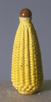 A yellow snuff bottle in the shape of an ear of corn.