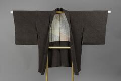 <p>Dark brown and gray Chirimen haori with shibori dyed latticework patterning with a white rinzu inner lining with dyed green, red and blue yosegire motifs</p>
