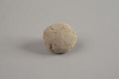 A white Indian terracotta sphere shape ball with cracks on it.