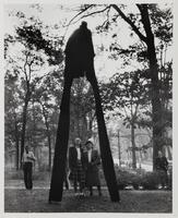 Image of a tall sculpture with long legs. Two women stand below the sculpture and look up at it, smiling.