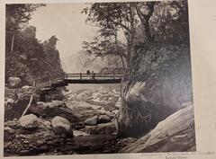 Two men standing on a bridge overlooking a very rocky river.&nbsp;