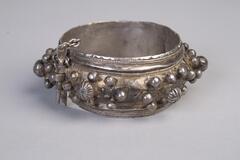 A silver cuff bracelet that has a pin lock to keep it closed.  The bracelet is decorated with silver beads.