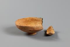 A ceramic lid for a matching bowl. Outfitted with a small, round and tapered handle.<br />
<br />
This yellow, low-fired earthenware vessel consists of a body and a lid. It is made from fine clay mixed with a small amount of fine sand particles. Fine, incised horizontal lines run around the body. The gallery that supports the lid rests at a slight incline, and the vessel mouth slopes slightly inwards. The lower part of the body rapidly tapers inwards before joining the base, the center of which is indented. The lid features a low, flat knob. The round, upper part of the lid meets the lip at a slight angle.[Korean Collection, University of Michigan Museum of Art (2017) p. 45]<br />
&nbsp;