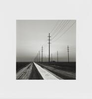 Black and white image of powerlines along a ditch.