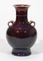An antique Chinese porcelain flambe vase. The vase is heavily potted, has a near globular body, narrowing neck with flared mouth, narrowing base with slightly broadened foor. The base is flat, unglazed with raised glazed centre. Two small dragon handles on the shoulder. The base has a lustrous blend of a red, bluish-purple glaze with an all-over minute delicate crackle.