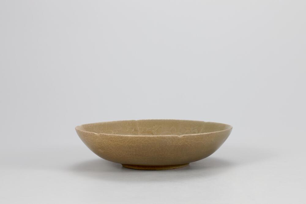 <p>This celadon bowl is decorated with mold-impressed designs, which was one of popular type of dishes in 11th and 12th centuries. On its inner walls are lotus scroll designs, and on its inner base is what is presumed to be a lotus flower design. Glaze has been applied all the way down to the rim of the foot, which retains traces of silica supports in three places. The yellow-green glaze is evenly spread on the surface, while the clay is of specially selected high quality, producing a smooth surface.<br />
[<em>Korean Collection, University of Michigan Museum of Art</em> (2014) p.111]</p>
<br />
shallow lobed bowl with molded lotus design on wall, 6 lobes, very small foot, high quality, need cleaning