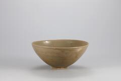 <p>This piece represents the archetype of Goryeo celadon made in the 11th century with its shape and designs displaying the in uence of Chinese Yue ware. e glaze was fused well to form a subtle gloss, while the clay body has a ne and dense texture. Around the interior rim is an incised line and also engraved are parrots and clouds below the line. There are four refractory spur marks on the foot.<br />
[<em>Korean Collection, University of Michigan Museum of Art</em> (2014) p.91]</p>
Stoneware teabowl with celadon glaze. A pair of parrots is incised on he inside of the bowl, as well as a line that runs slightly below and parallel to the rim.