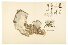Japanese style ink painting of a pot with vegetation inside of it next to a stone. The image is colored, with the rock painted in a grayish ink and the vegetation a green color. The pot has no color but is outlined in black ink only. There is writing in the top right corner of the paper.