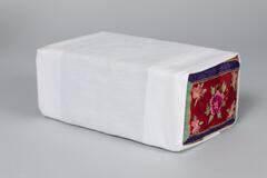 Wood rectangular pillow covered in white cotton slip with embroidered flowers on the end. The base is green with a geometric border and embroidered pink, purple, and white flowers.