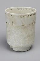 White glazed vase with cut out detail on top.