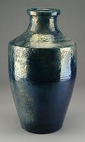This is a tall vase with an oval shaped body. It has a short neck with a flat banded lip and the shoulder has a distinct, but rounded edge. It has a dark blue glaze and the upper portion has a golden iridescent color. The surface of the pottery is very rough with bumps and rough patches.