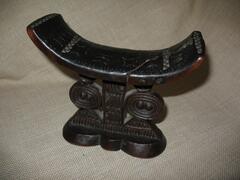 Zimbabwe, with geometric carving.<br />
Headrests are small furnishings, typically sculpted from wood. They frequently have a concave platform supported by legs, though the platform can also be flat and/or be supported by a central post that may be connected to a broad base. The platform may be cushioned to provide comfort for the owner&rsquo;s head, and many headrests feature complex ornamentation and sculptural details. Headrests share some of the same motifs and associations with stools, as they are constructed similarly and used for similar purposes.