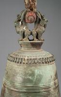 Bronze temple bell with traces of polychrome, text, and lowermost handle in shape of a pair of addorsed lions. A decorated post threads through the space created by the back-to-back lions, on which an additional handle decorated with addorsed dragons is thread. The open space created between the dragons&#39; connecting tails is where part of a frame would pass through, suspending the bell above the ground. This type of bell does not have a metal clapper, and is rung by striking with a wooden stick.