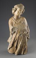This sculpture represents an angel bending slightly toward the left with his head tilted downward. Carved slots in his back would have held his wings, and the figure has lost his forearms and hands as well as his legs below the knees.