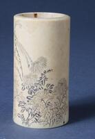 An ivory brush holder with depictions of flowers and leaves.