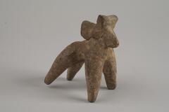 Indian terracotta figure of a dog with its head facing back and four legs standing.