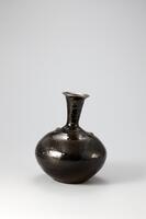 Many black-glazed vessels of this type were produced in the areas of Jeongok-ri, Uijeongbu-si, and Yeoju-si in Gyeonggi-do in the late 19th and early 20th centuries. Made from coarse, colored clay, its black-glazed surface shines like that of porcelain. It has a lot of sand and bubbles on its surface, producing a rough texture, while fragments of other vessels have become embedded in its shoulder section during firing, but its glaze is well fused, producing a smooth sheen.<br />
[Korean Collection, University of Michigan Museum of Art (2014) p.211]