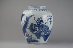This porcelain jar tapers to a base with a recessed foot ring, and has wide, softly rounded shoulders leading up to a wide neck. It is painted with underglaze cobalt blue to depict a key-fret border around the neck, with banana leaf lappets around the shoulder, and two <em>qilin</em> (麒麟) in a mountainous landscape with <em>lingzhi</em>-shaped clouds. It is covered in a clear glaze, and has an unmarked base. 